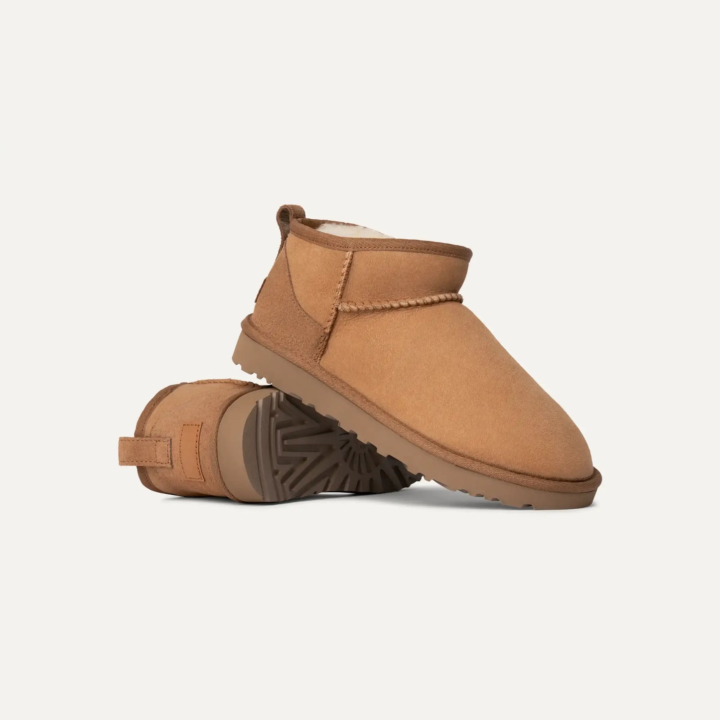 Chestnut suede ultra mini boots, one lifted to show treaded sole