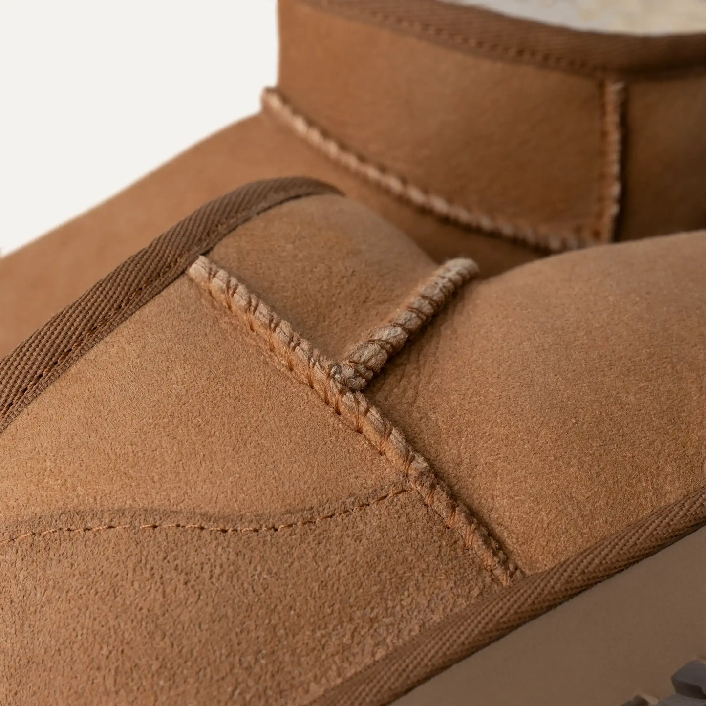 Chestnut suede boot upper close-up with stitched seam and padded collar