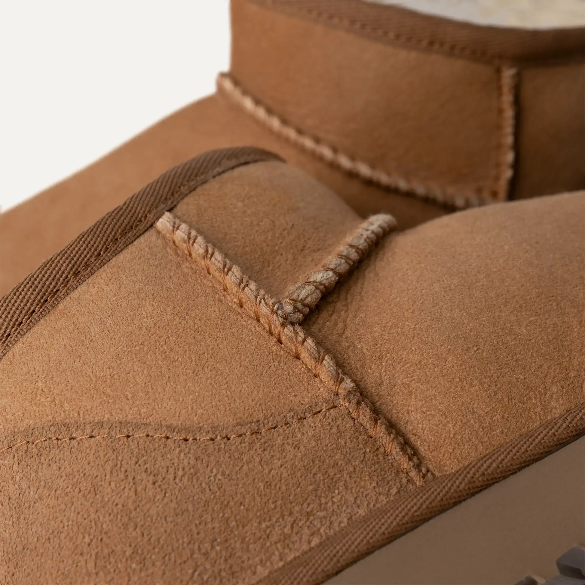 Chestnut suede boot upper close-up with stitched seam and padded collar