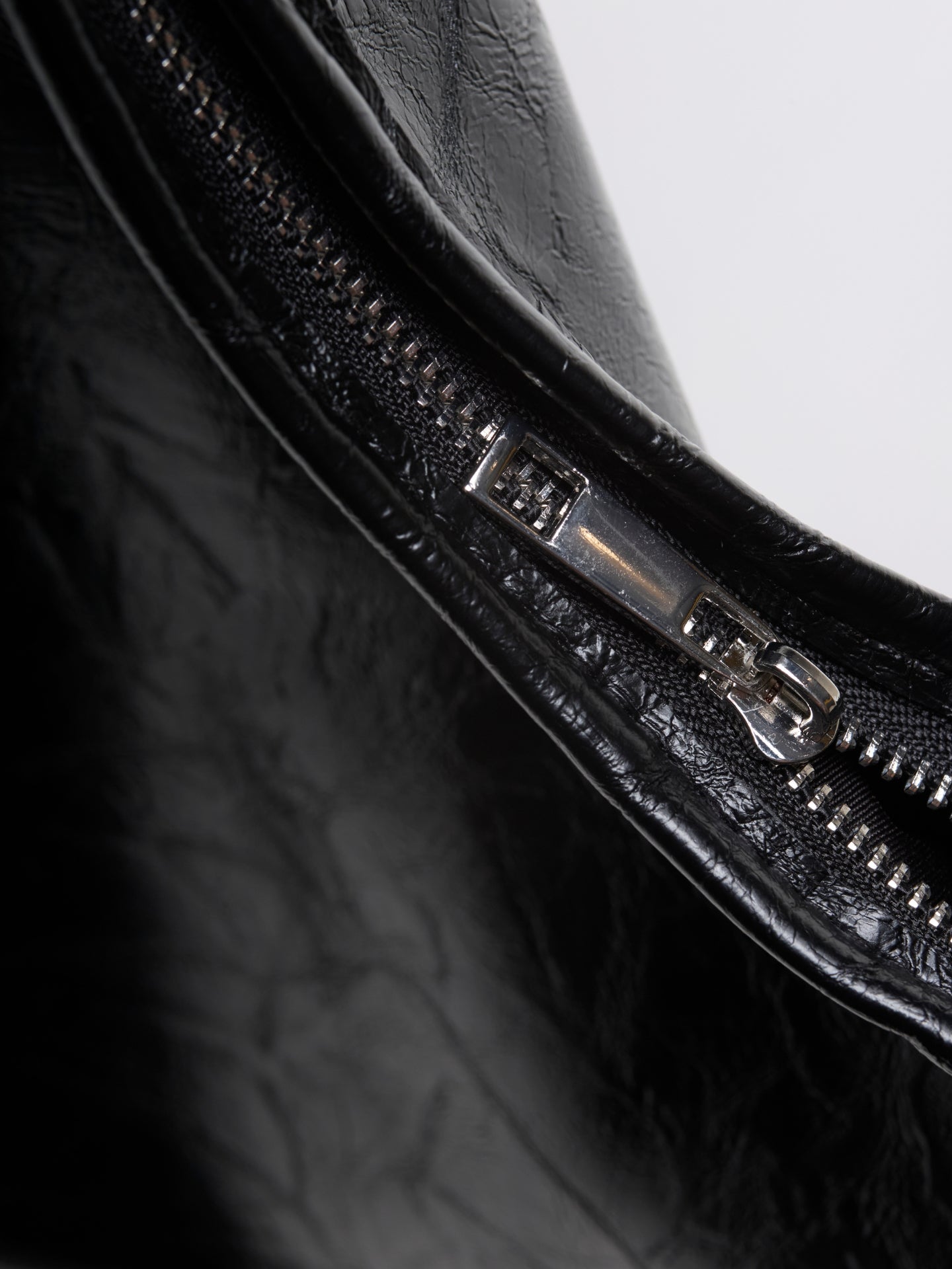 Distressed vegan leather tote bag close-up of black zipper and stitched trim