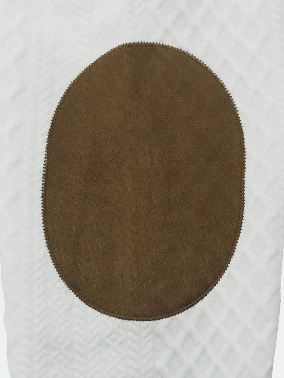 Brown circular suede patch on white cable-knit fabric