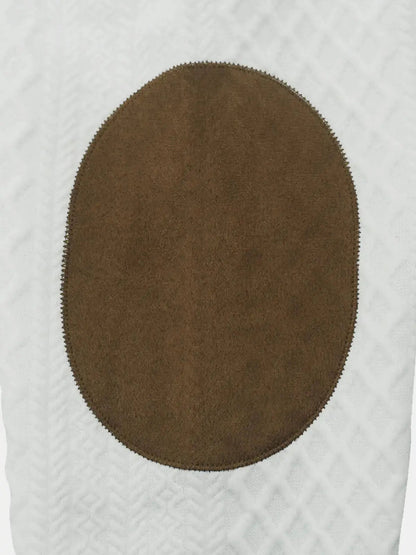 Brown circular suede patch on white cable-knit fabric