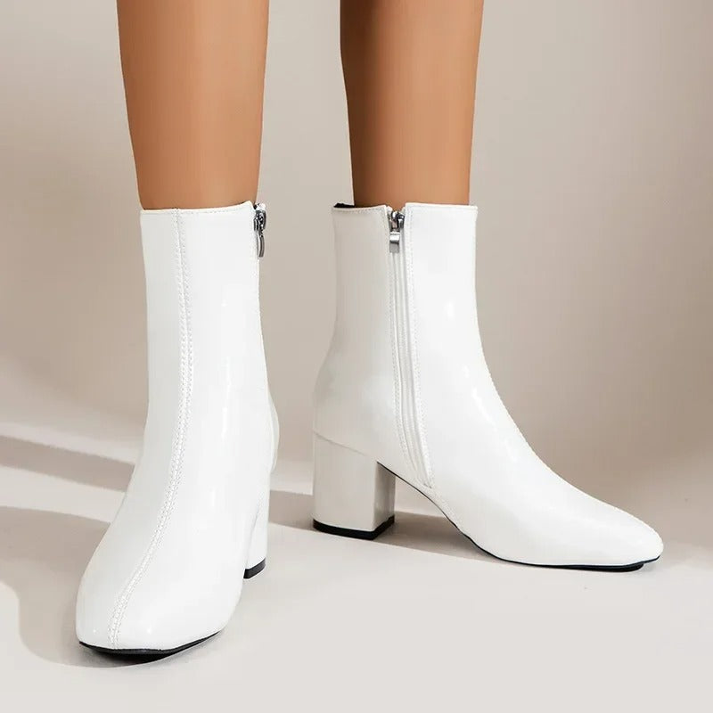 White ankle boots with side zipper and mid block heel, sleek pointed toe.