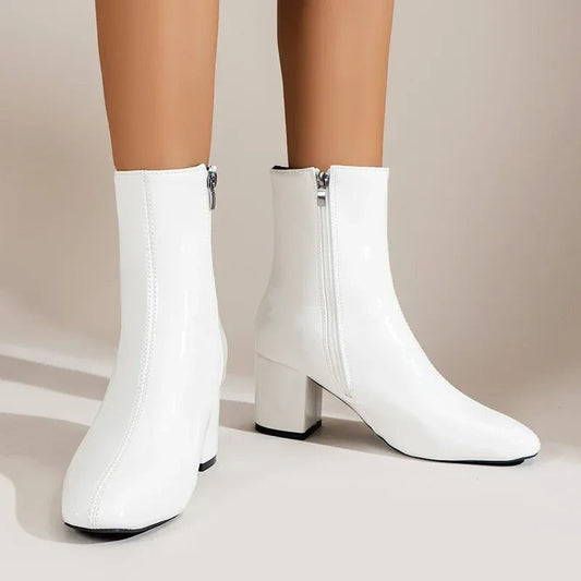 White ankle boots with side zipper and mid block heel, sleek pointed toe.