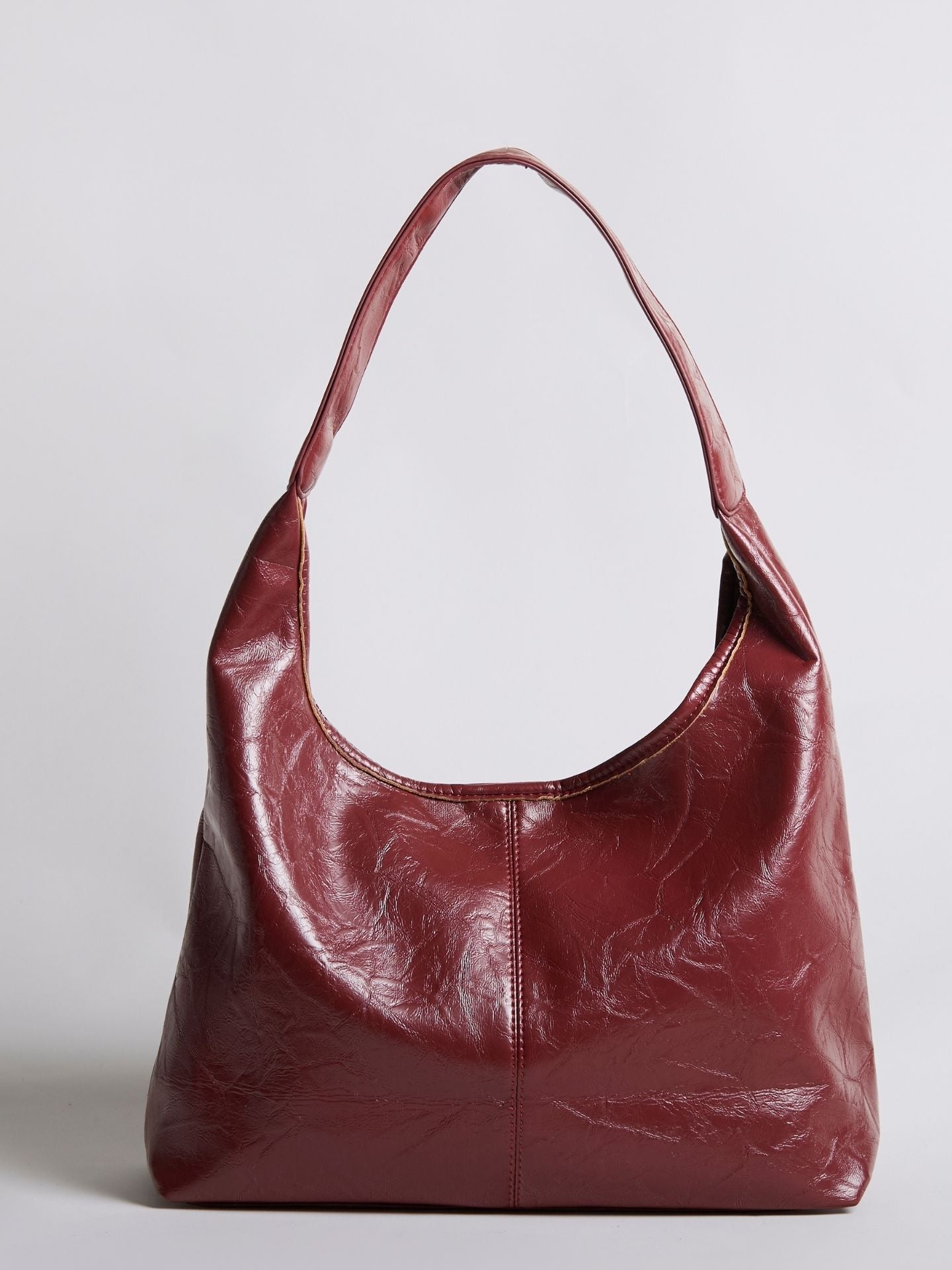 Red distressed vegan leather tote bag with curved top opening and wide shoulder handles.