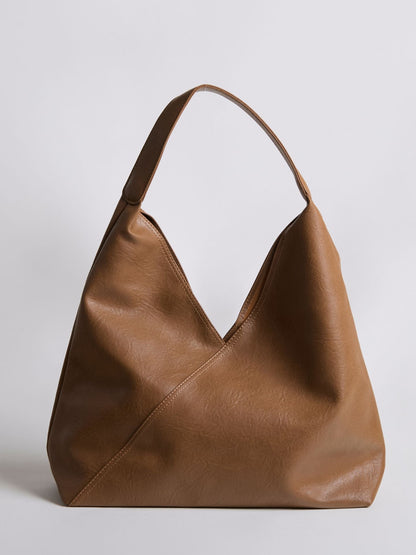 Tan leather shoulder bag with wide top handle and V-shaped open front.