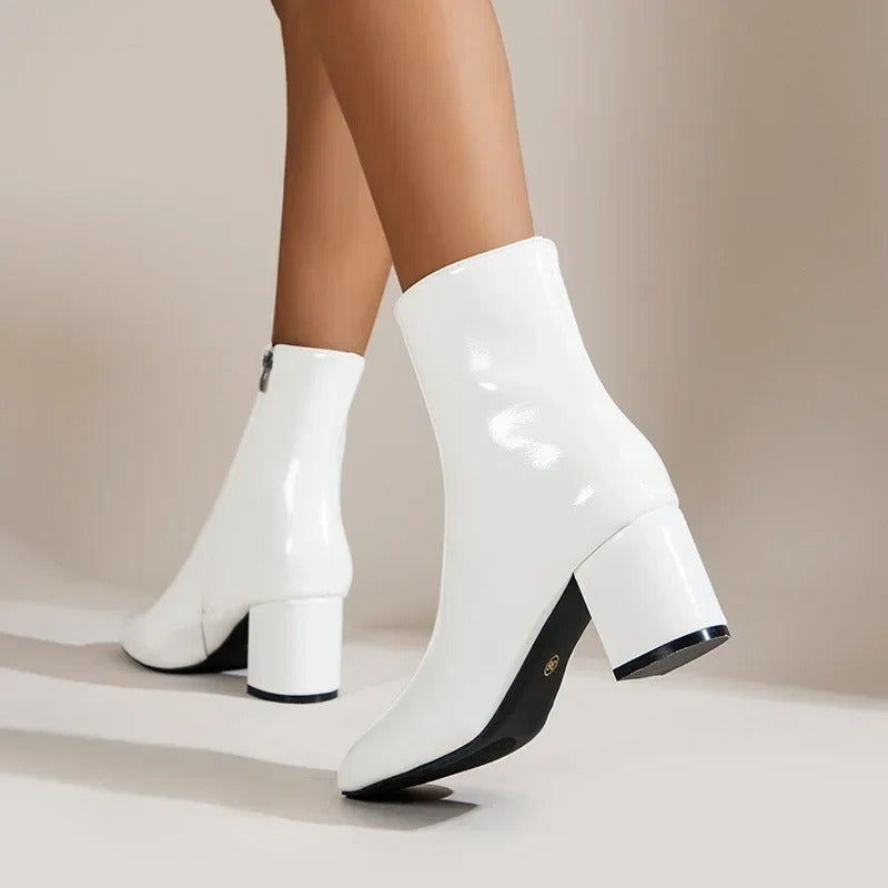 White glossy ankle boots with side zipper, mid block heel, pointed toe profile.