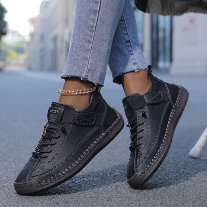 Black slip-on trainers with lace-up front and ankle strap, textured rubber sole