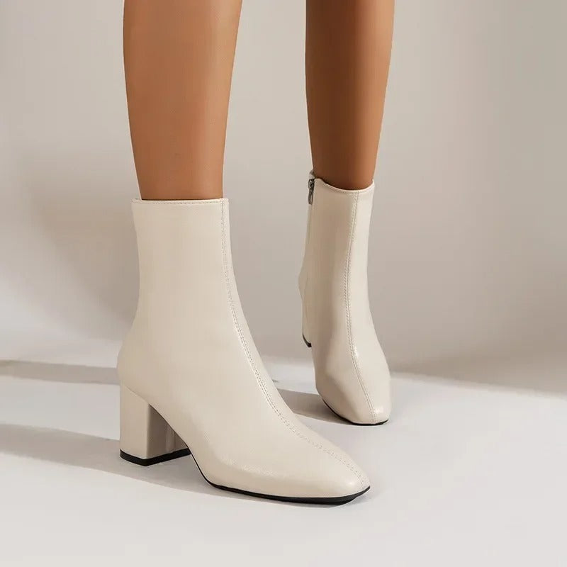 Cream beige ankle boots with side zipper and mid block heel, pointed toe and short shaft.