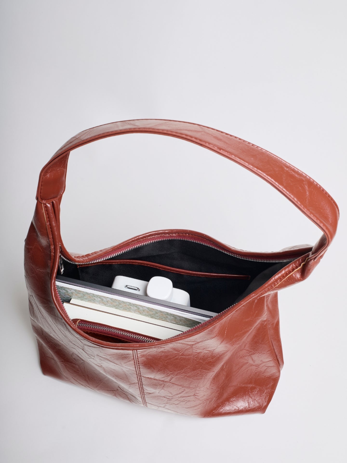 Brown vegan leather tote bag interior view with top zipper and inner slip pockets.