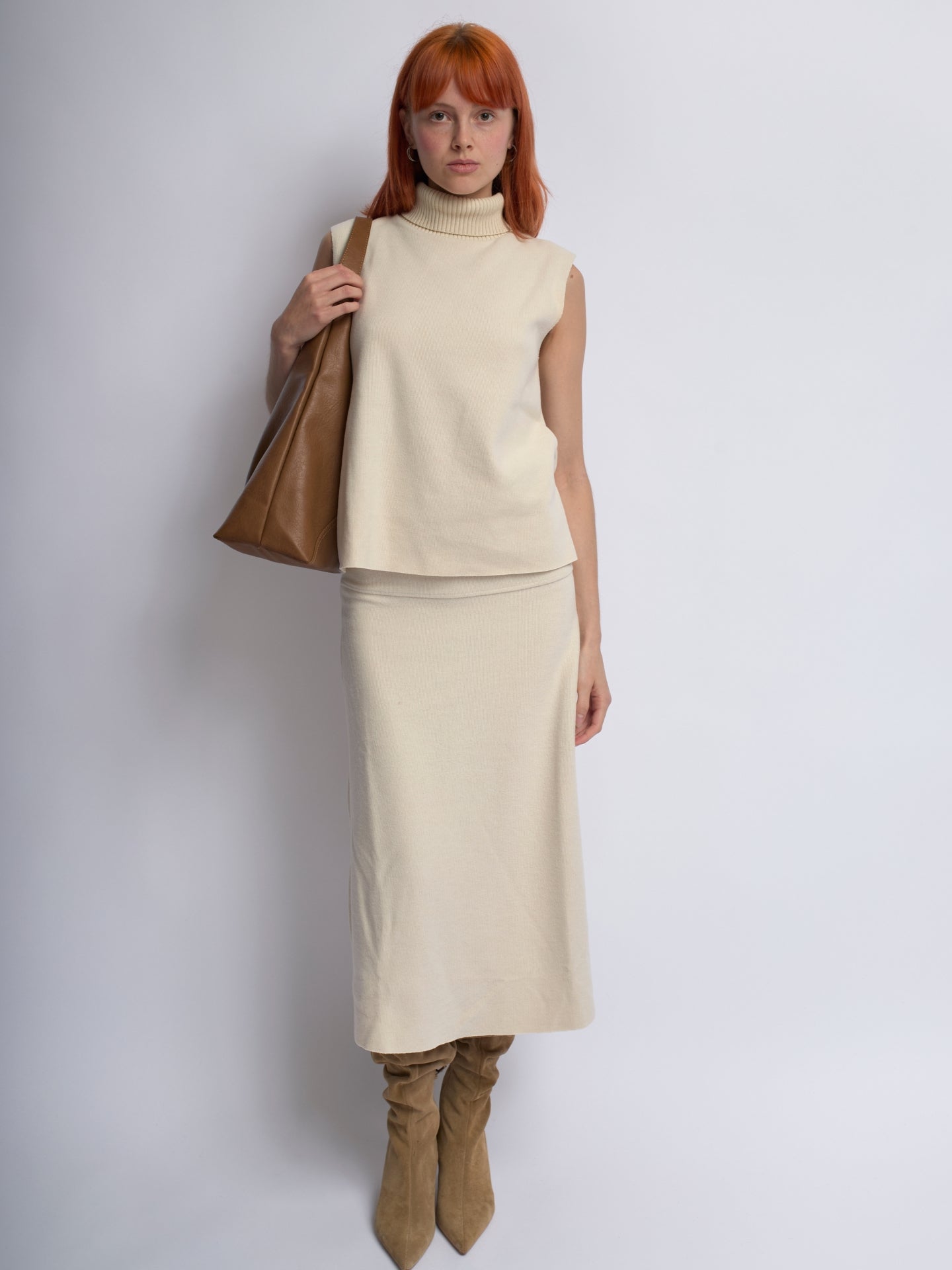 Tan leather shoulder bag held at shoulder, soft slouchy shape and top handle straps