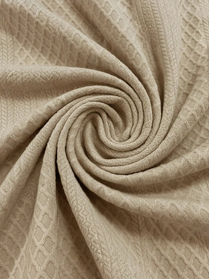 Beige cable knit fabric close-up with diamond texture pattern