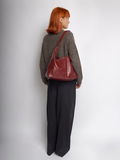 Burgundy distressed vegan leather tote bag worn over shoulder, back view
