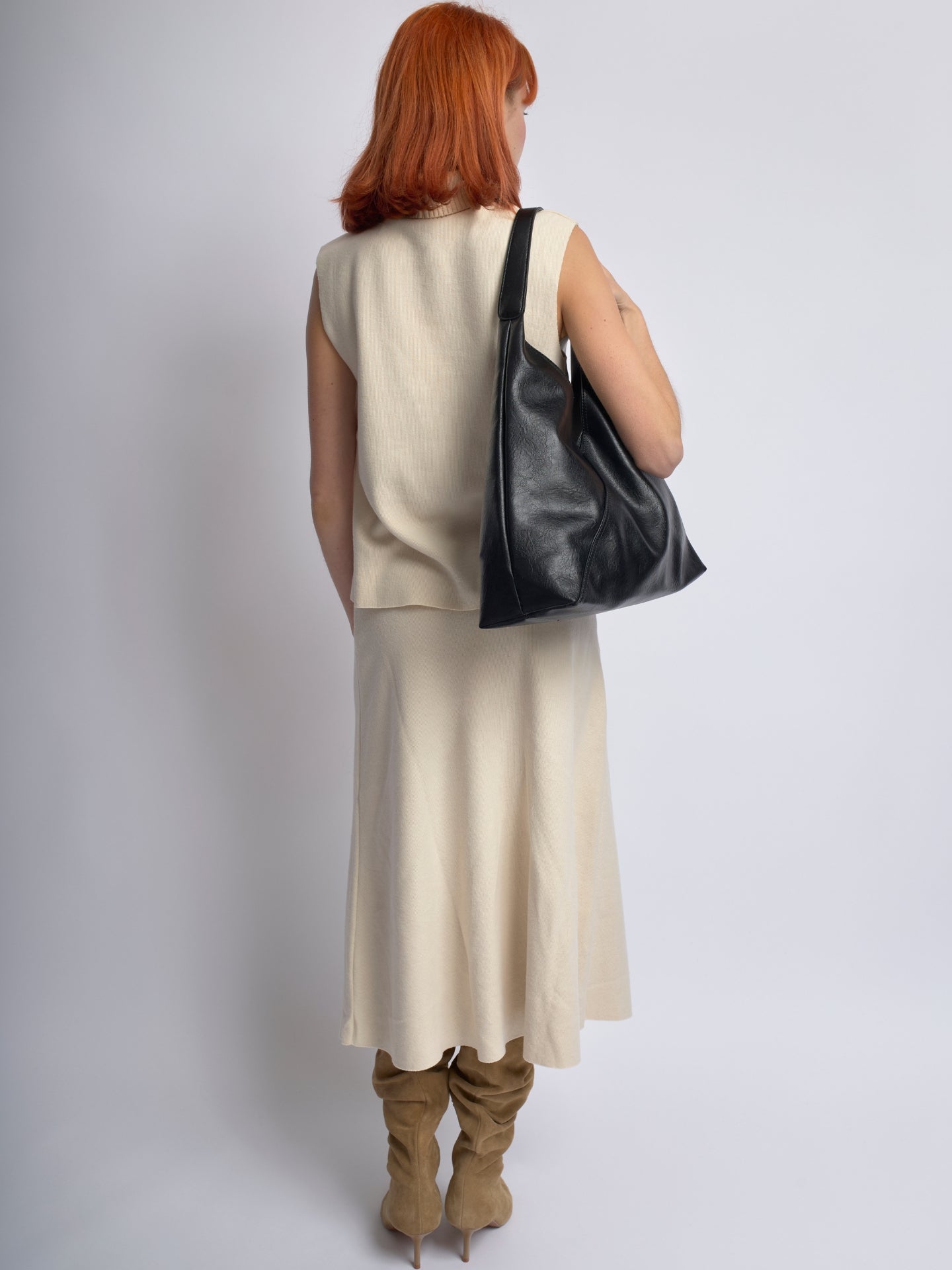 Black leather shoulder bag viewed from the back, slouchy silhouette and wide strap