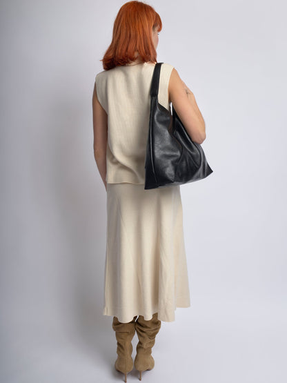 Black leather shoulder bag viewed from the back, slouchy silhouette and wide strap