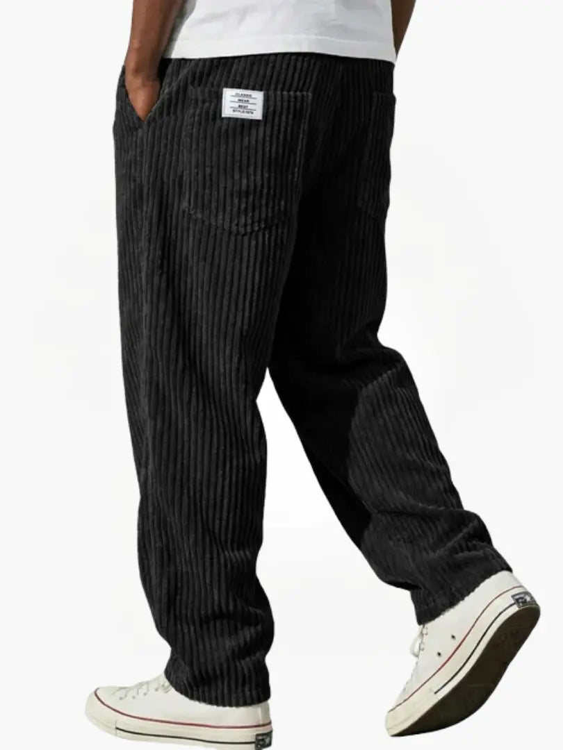 Wide-leg men's trousers with pockets in black vertical cord texture.