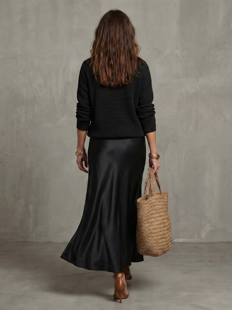 Black satin bias midi skirt with knit V-neck top, back view and hem drape