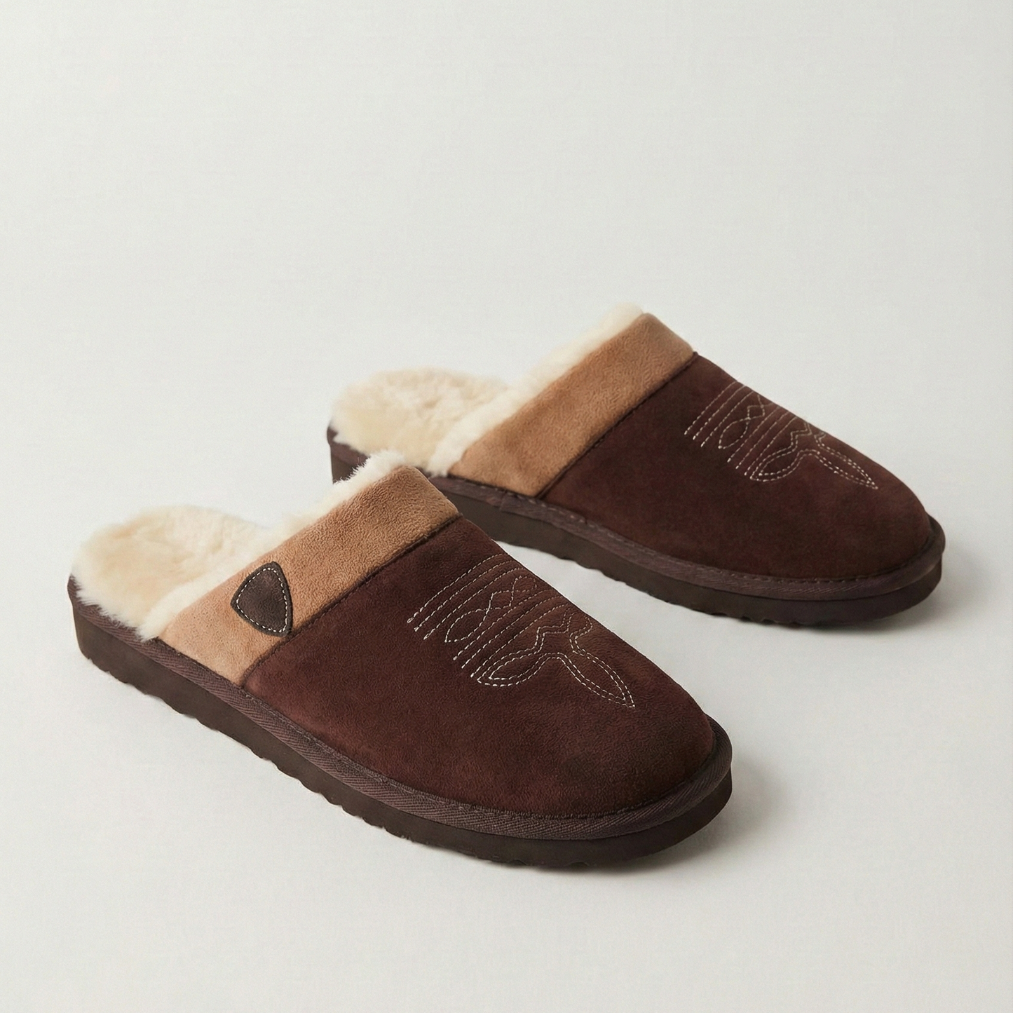 Cowboy slippers in brown and darker brown, both with faux-fur lining and stitched detail.