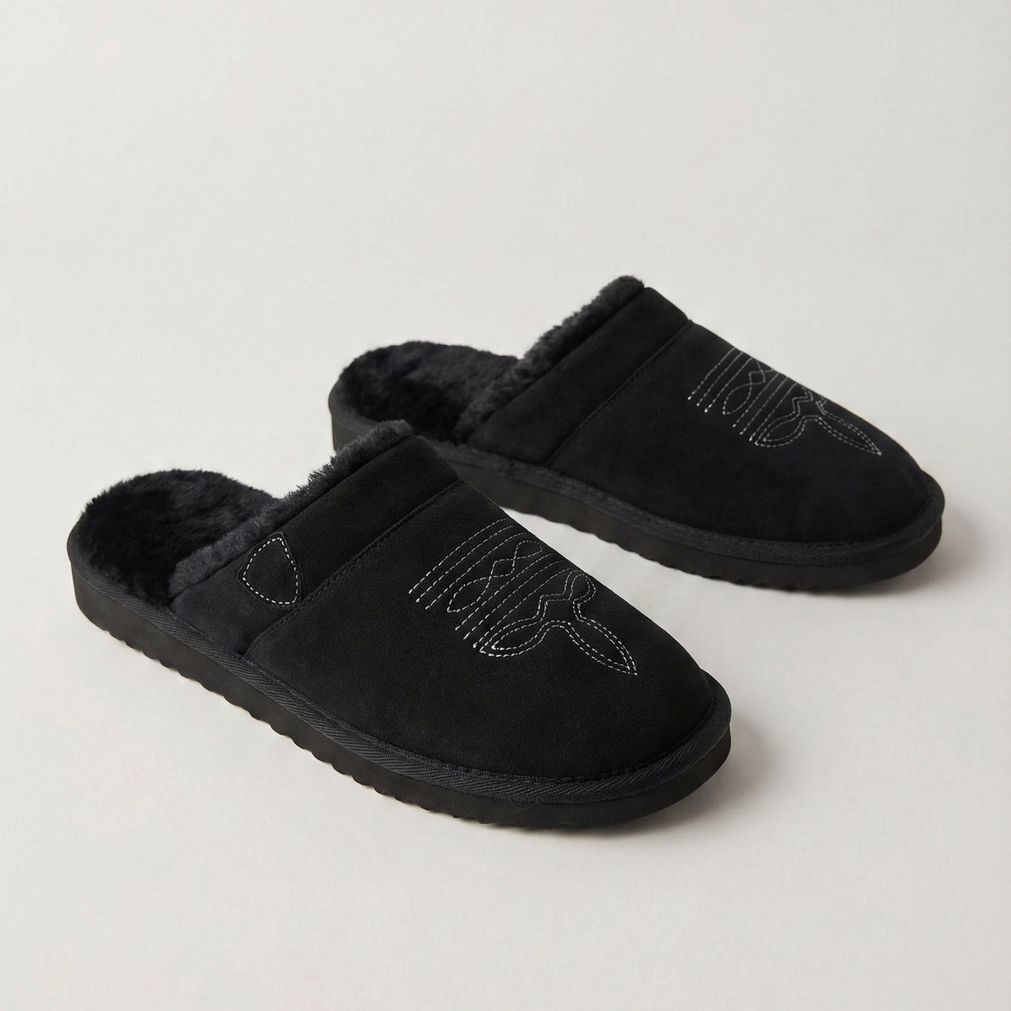 Pair of black slip-on cowboy slippers with faux-fur lining and curved stitch design
