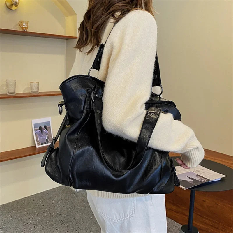 Black vegan leather handbag with two top handles and a detachable crossbody strap