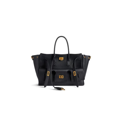 Black structured handbag with side pockets and gold-tone hardware, three-quarter view