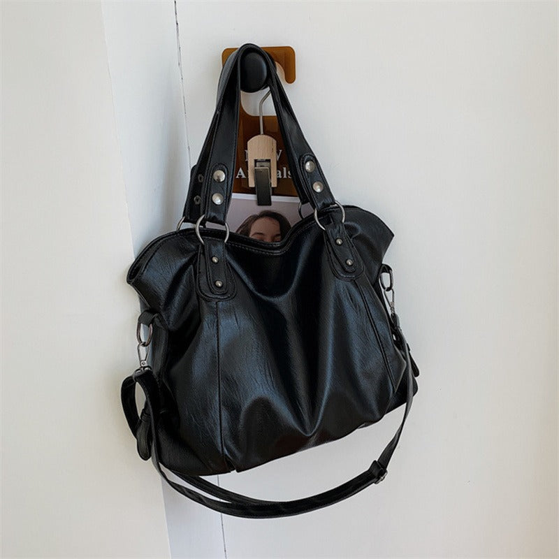 Black vegan leather handbag hanging with two top handles and side zipper detailing
