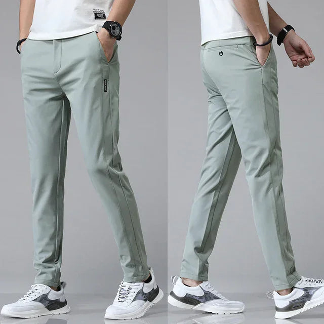 Slim-fit light green pants with tapered legs and zip pocket detail