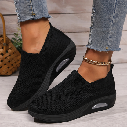 Black knit slip-on walking shoe with cushioned sole and oval air-cushion window