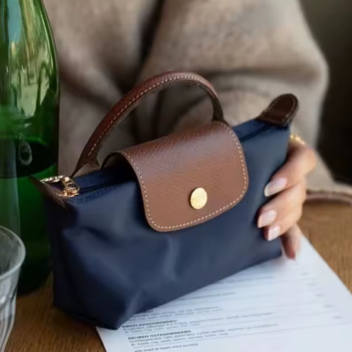 Mini leather pouch, dark navy with brown front flap and gold snap, short handles and strap