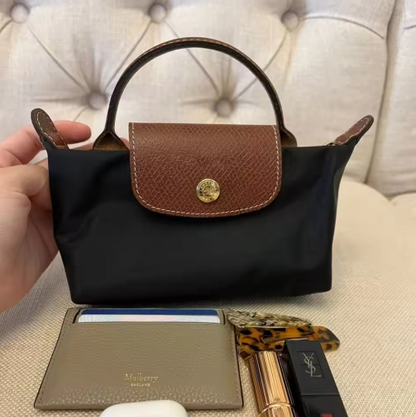 Mini leather pouch, black with brown front flap and gold snap, top handle and shoulder strap