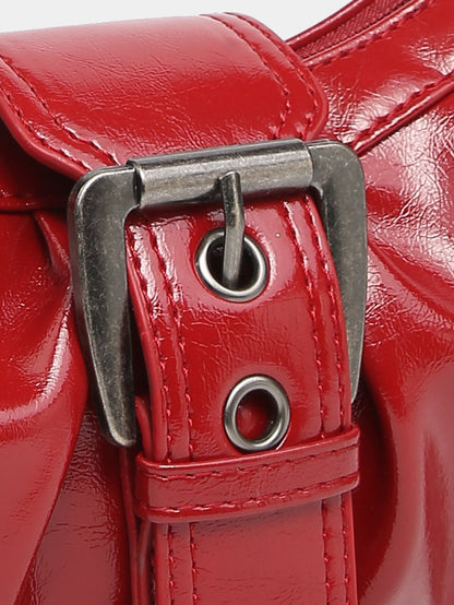 Close-up of red faux leather hobo bag buckle strap with metal D-ring and grommet