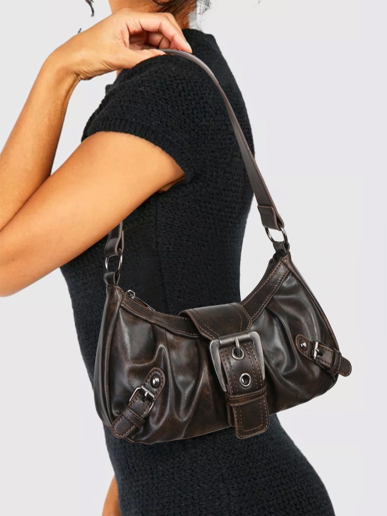 Brown faux leather hobo bag worn crossbody with adjustable strap and front buckle hardware