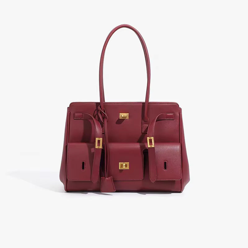 Maroon structured handbag with side pockets and gold-tone hardware, angled view