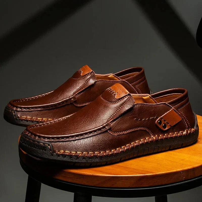 Men's brown leather loafer with moc-toe stitching and strap with metal eyelet