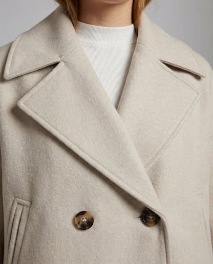 Cropped double-breasted jacket lapel close-up in light beige with gold-tone buttons
