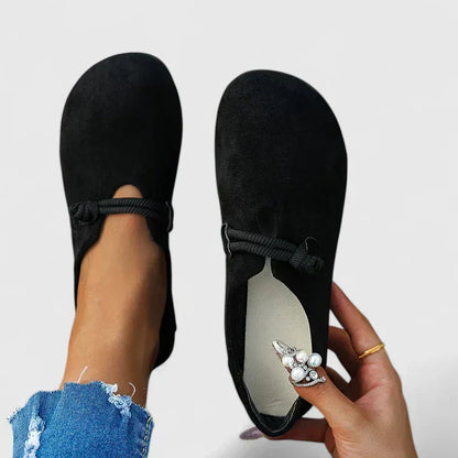 Black slip-on walking shoes with heel loop strap and bow detail