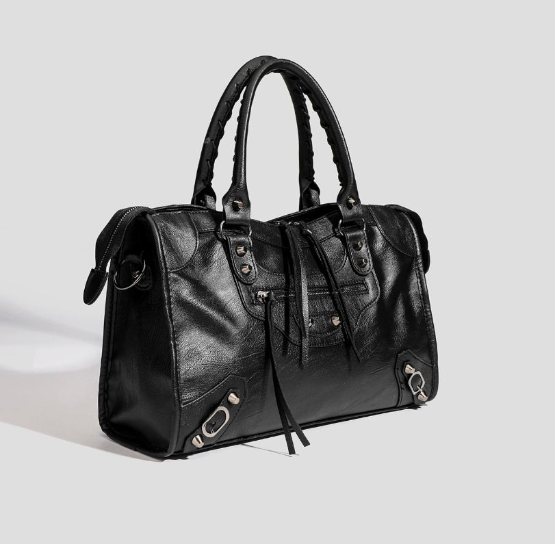 Black vegan leather tote bag side view with tassel ties and front zipper pocket