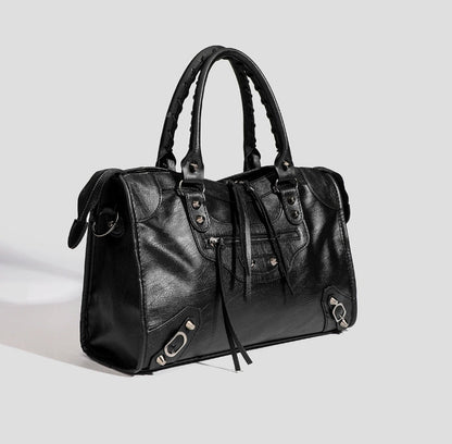 Black vegan leather tote bag side view with tassel ties and front zipper pocket