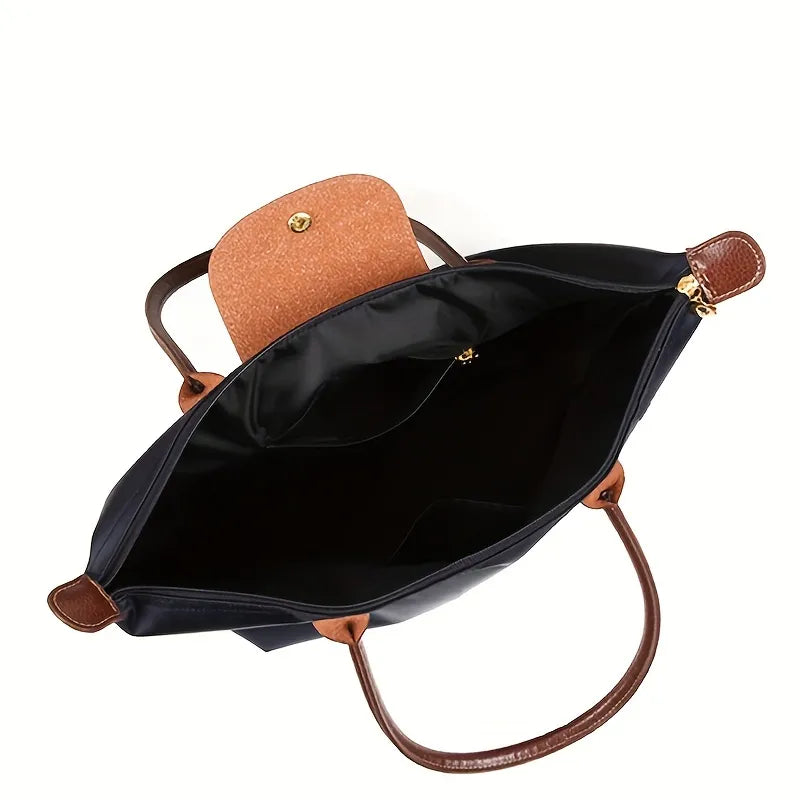 Black open-top shoulder tote with brown leather handles and tan interior panel