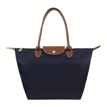 Navy structured shoulder tote with brown leather trim, front flap snap, gold side detail