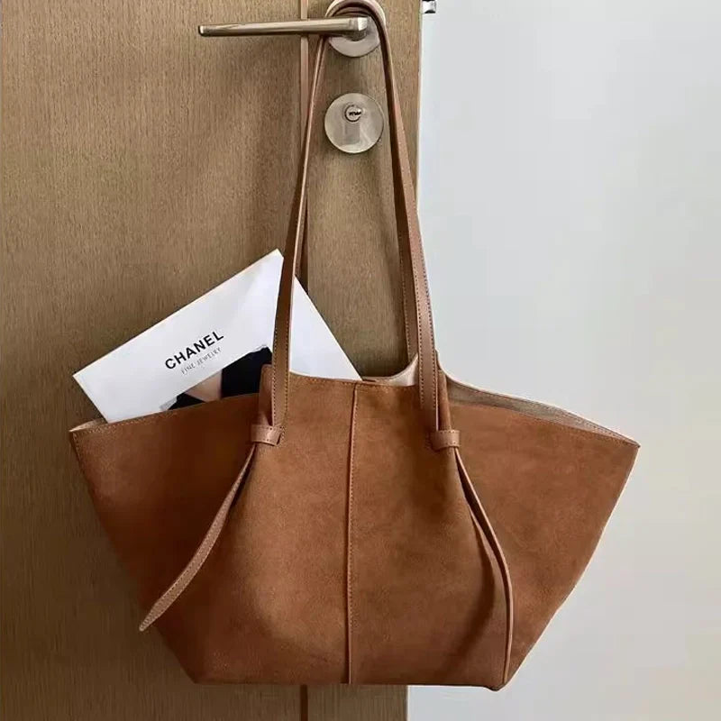 Tan suede tote bag with dual handles and metal top clasp