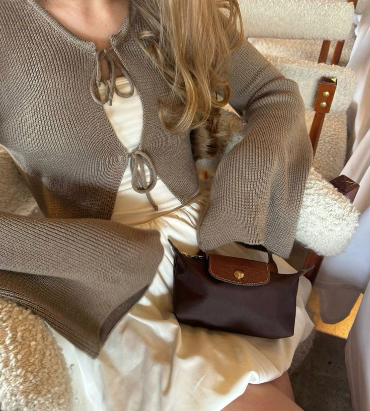 Mini leather pouch in dark brown with tan front flap, gold snap, top handle and crossbody strap