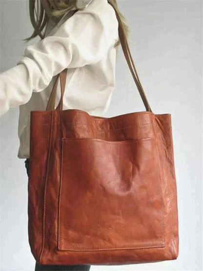 Tan/brown leather tote bag with wide handles and front pocket panel