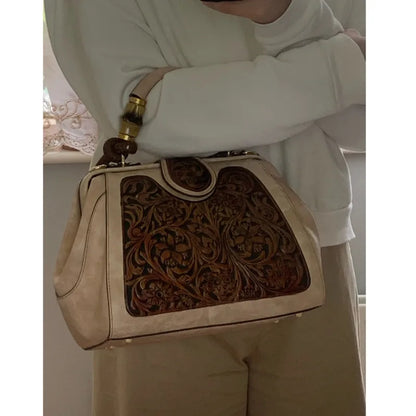 Beige leather handbag with ornate brown floral embossing and gold-tone handles