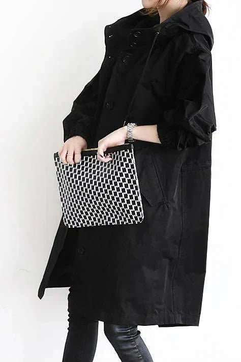 Women’s raincoat in black with oversized hood and button-front, side pocket details.