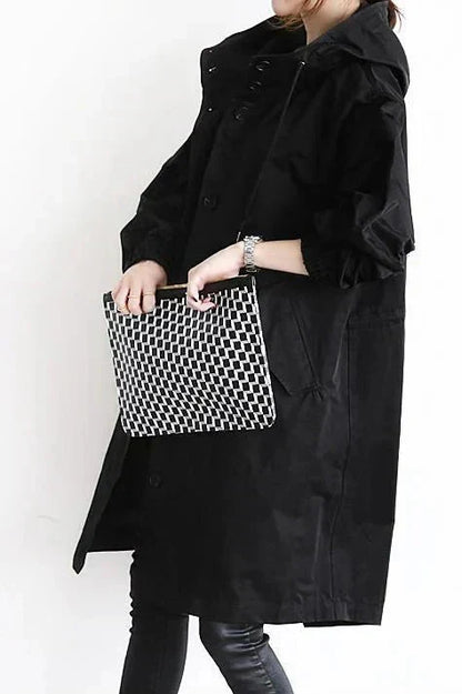 Women’s raincoat in black with oversized hood and button-front, side pocket details.