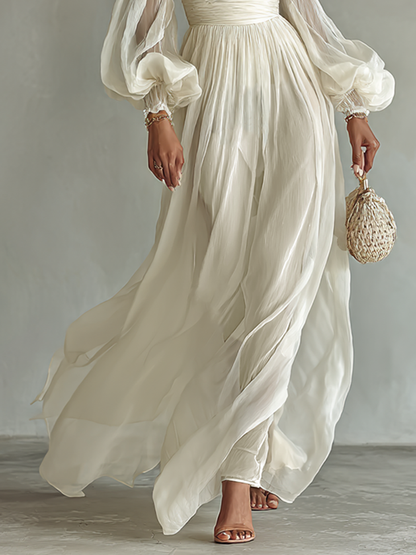 White chiffon maxi skirt with flowing pleats and cinched waist, long puff sleeves