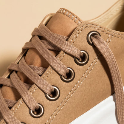 Tan platform sneaker close-up: lace eyelets and top stitching on the upper