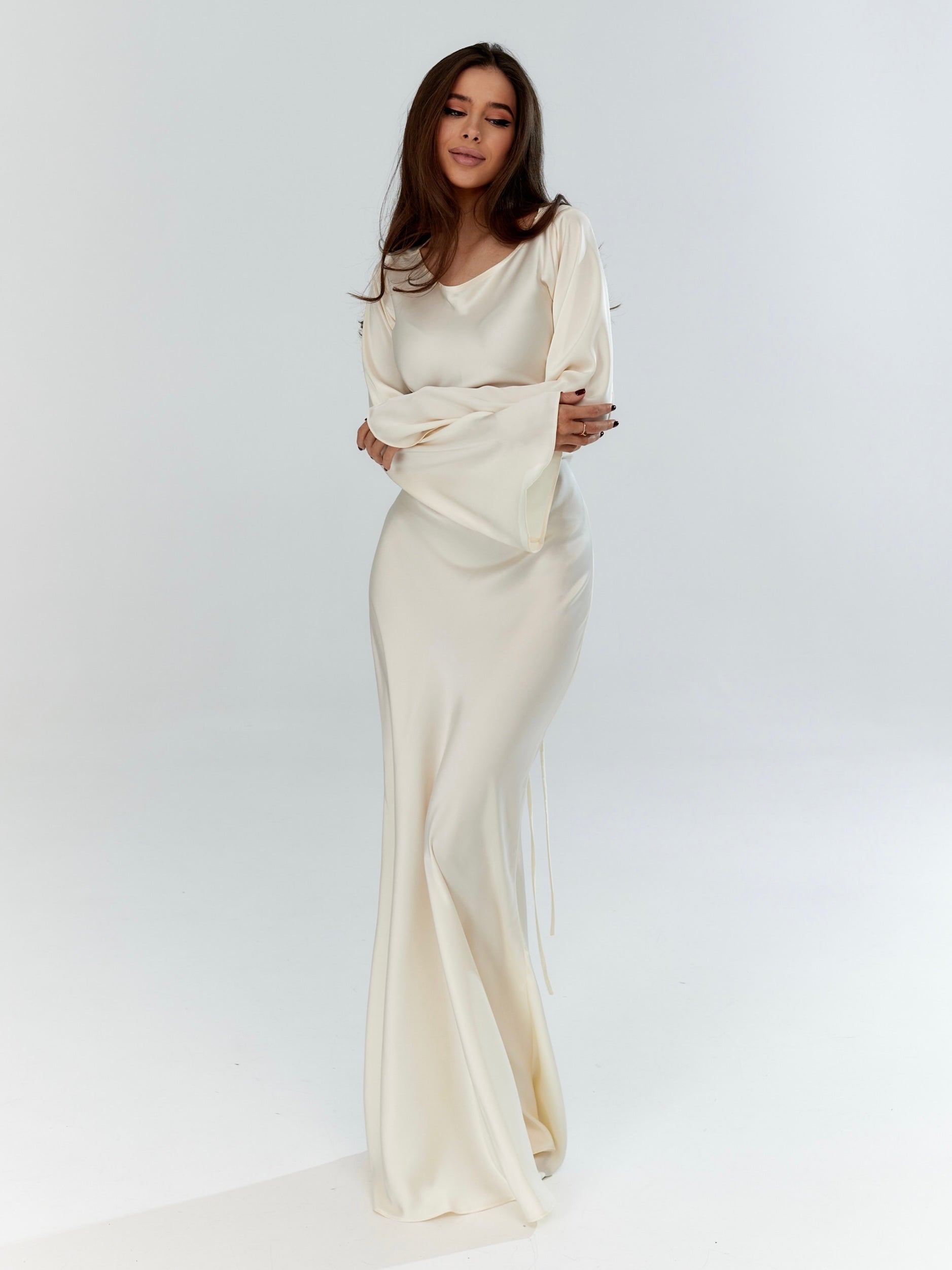 Long-sleeved maxi dress in off-white with fitted bodice and draped skirt