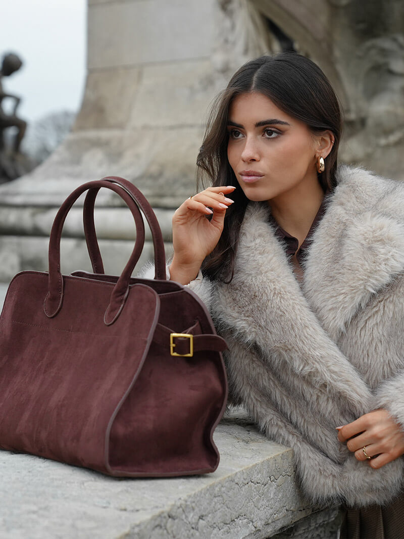 Burgundy suede handbag with top handles, gold buckle strap detail